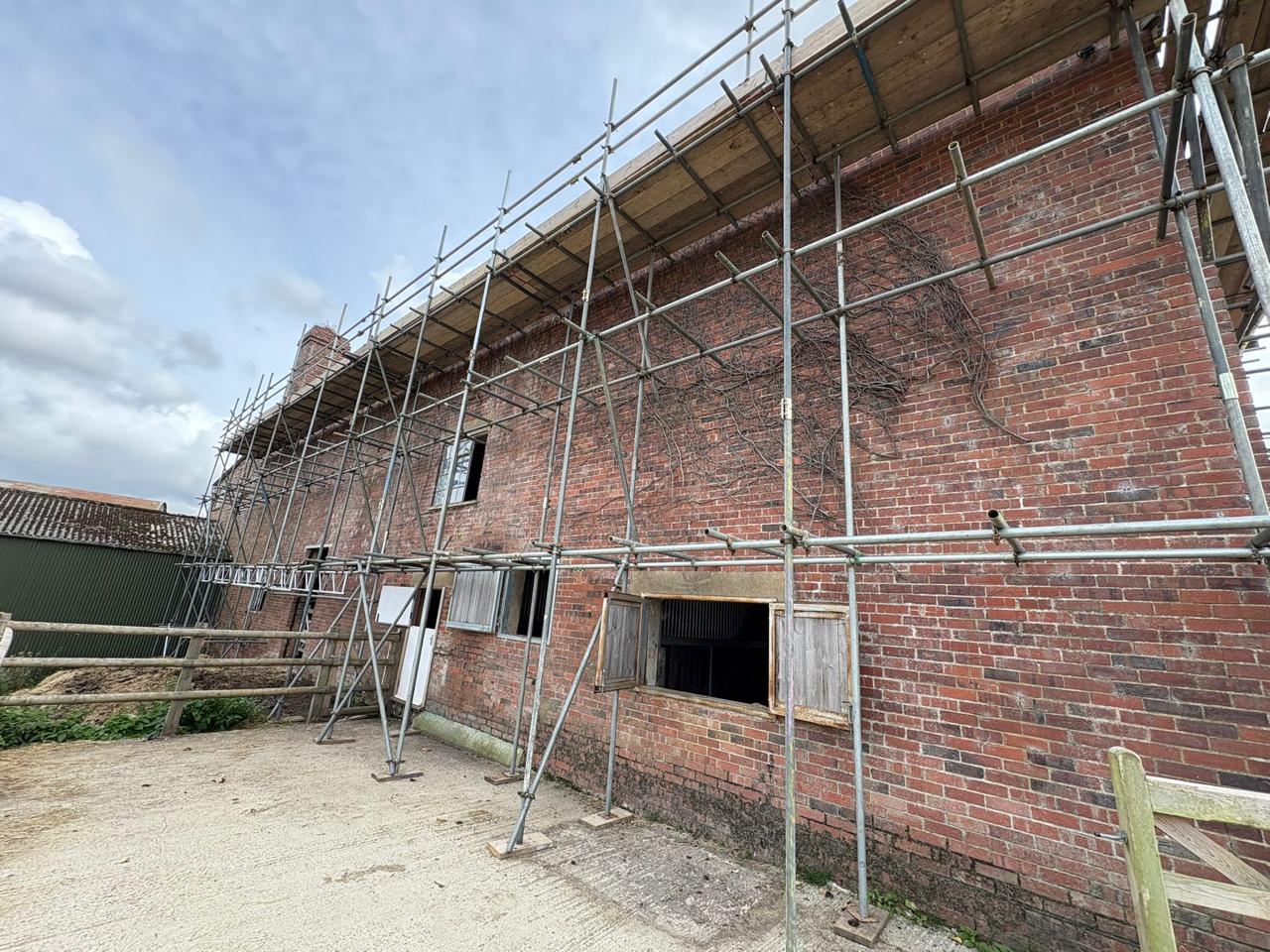 Boarded scaffold lifts and guardrails built tight against brickwork on a Kent project